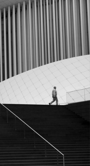 Lone figure on a spiral concrete staircase, in black and white